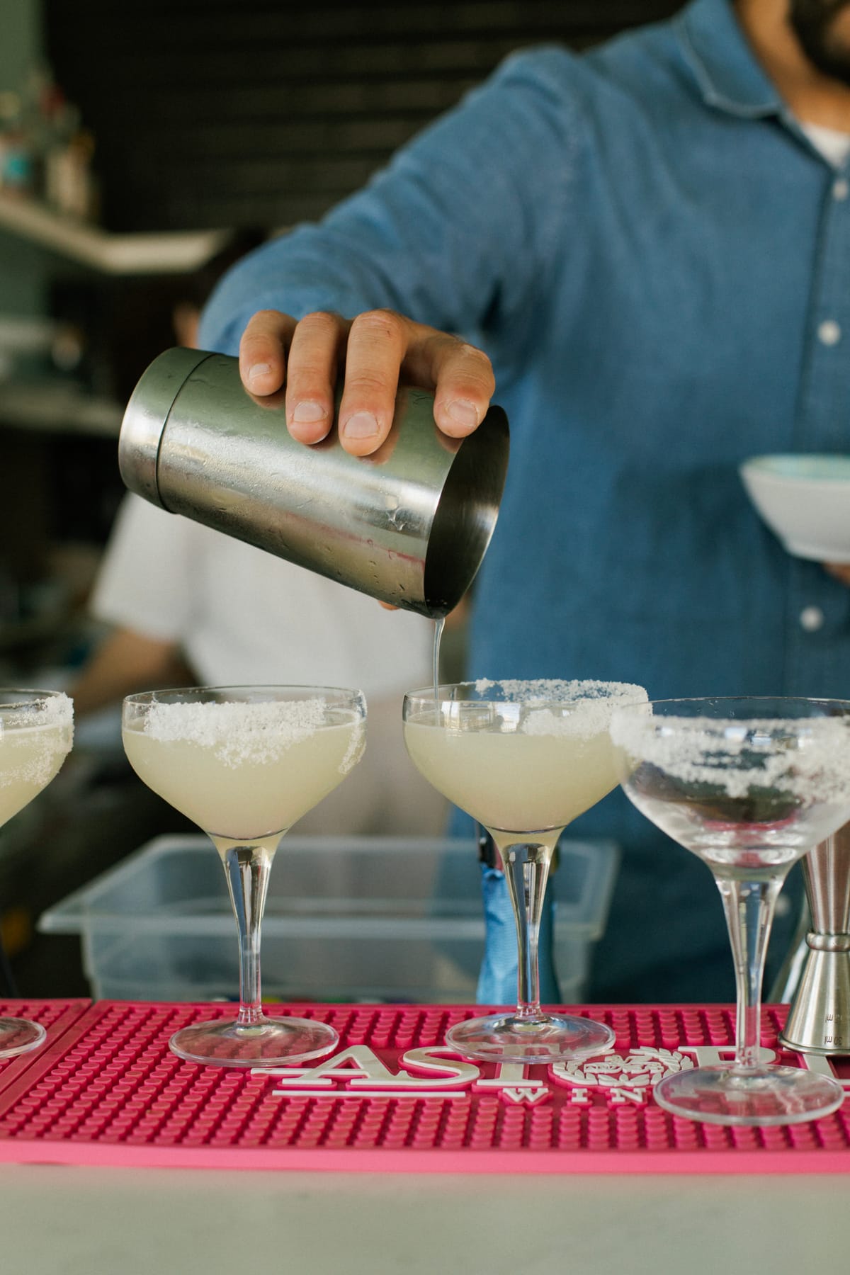 Barman che versa cocktail in coppette ghiacciate dietro il bancone
