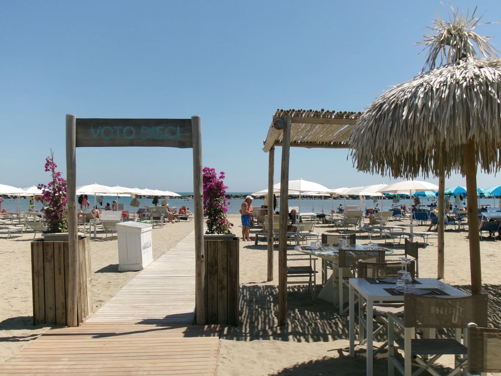 Panorama della spiaggia del Maracuja con ombrelloni bianchi, tavoli e mare sullo sfondo